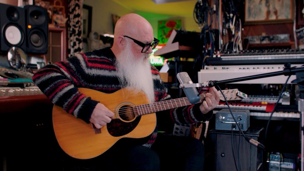 Dave Catching, a man with a long white beard playing acoustic guitar in front of a Mojave MA-37 microphone.